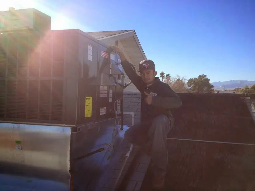 HVAC technician performing Air Duct Cleaning on a rooftop unit in Alamo